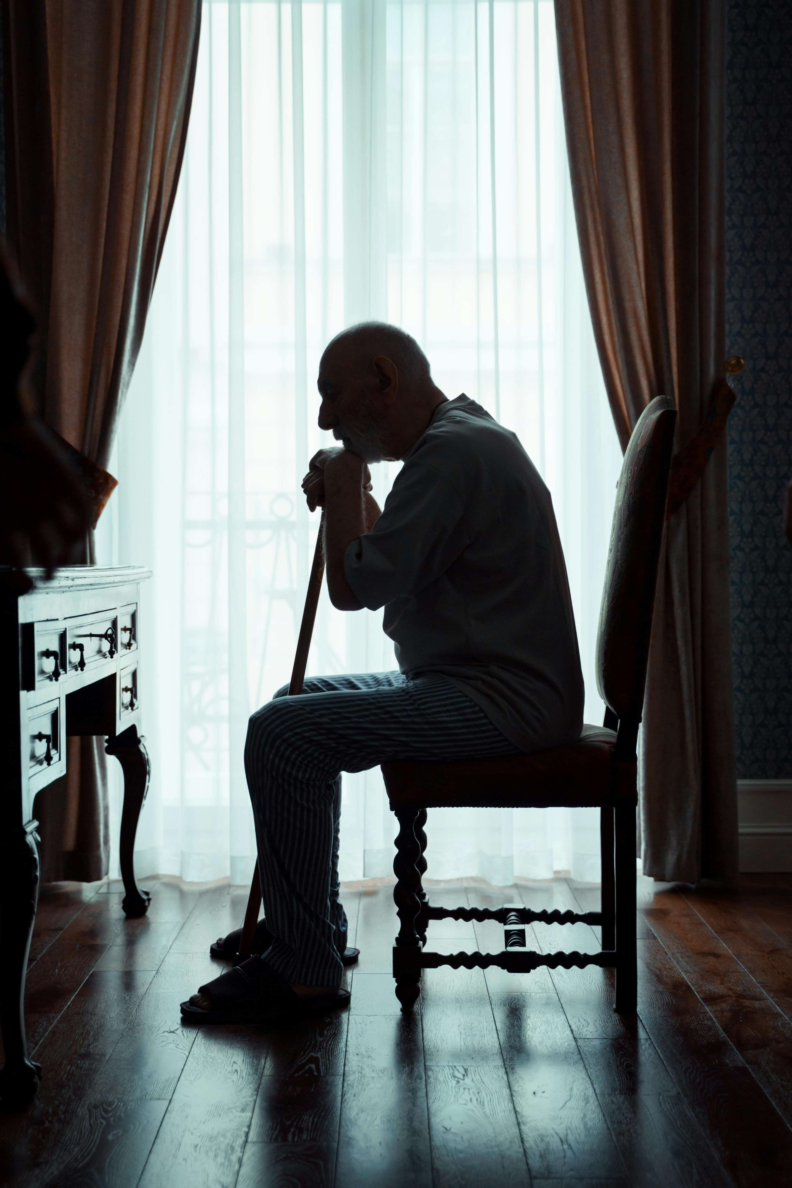 An older adult sitting quietly alone at home